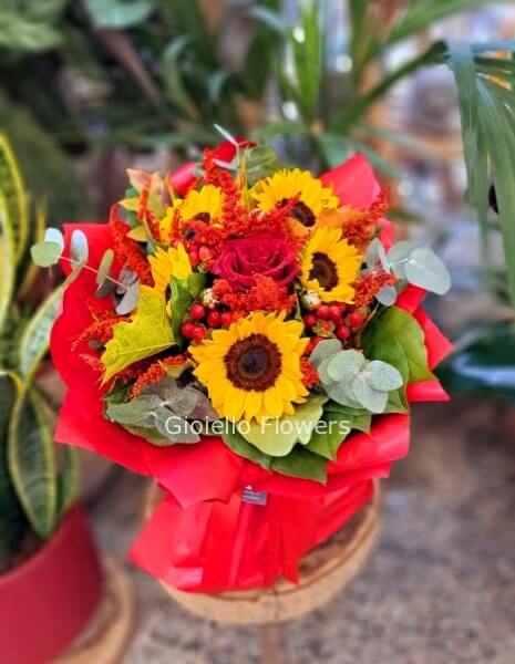 Bouquet laurea con girasoli e fiori assortiti tonalità rosso