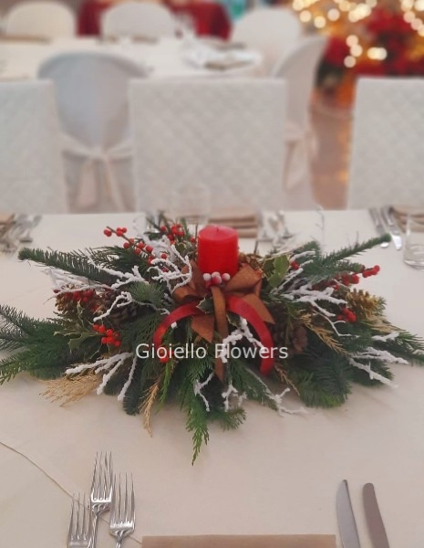 Centrotavola natalizio rosso, con candel, bacche e abete.